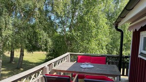 Um deck de madeira com uma mesa e cadeiras, rodeado por árvores.
