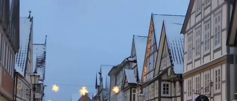 A snow-covered street with traditional European architecture, including half-timbered buildings and a clear sky.