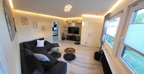 A modern living room with a sofa, coffee table, and artwork on the walls. - Vacation rental, approx. 47 square meters, garden, patio—dogs are welcome! (Celle)