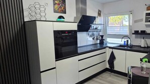 Une cuisine moderne avec des meubles blancs, un four noir et une fenêtre qui laisse entrer la lumière naturelle.