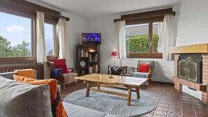 Una sala de estar acogedora con chimenea, televisor y estantería.