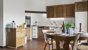 Una cocina con armarios de madera, una mesa de comedor para cuatro personas y una lámpara colgante.