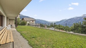 Un edificio con un patio techado, zona verde y vista a la montaña.