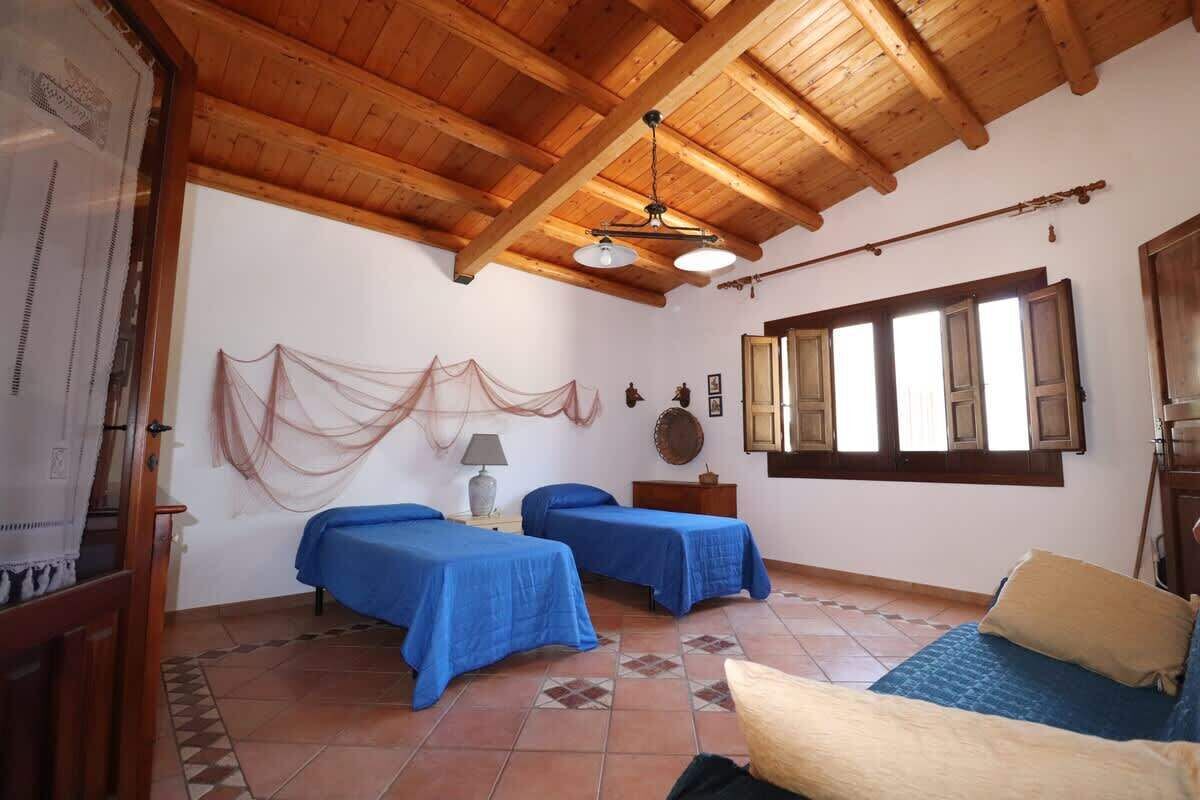 Une chambre avec deux lits, un plafond en bois, une fenêtre avec des volets et une lampe sur une table de chevet.