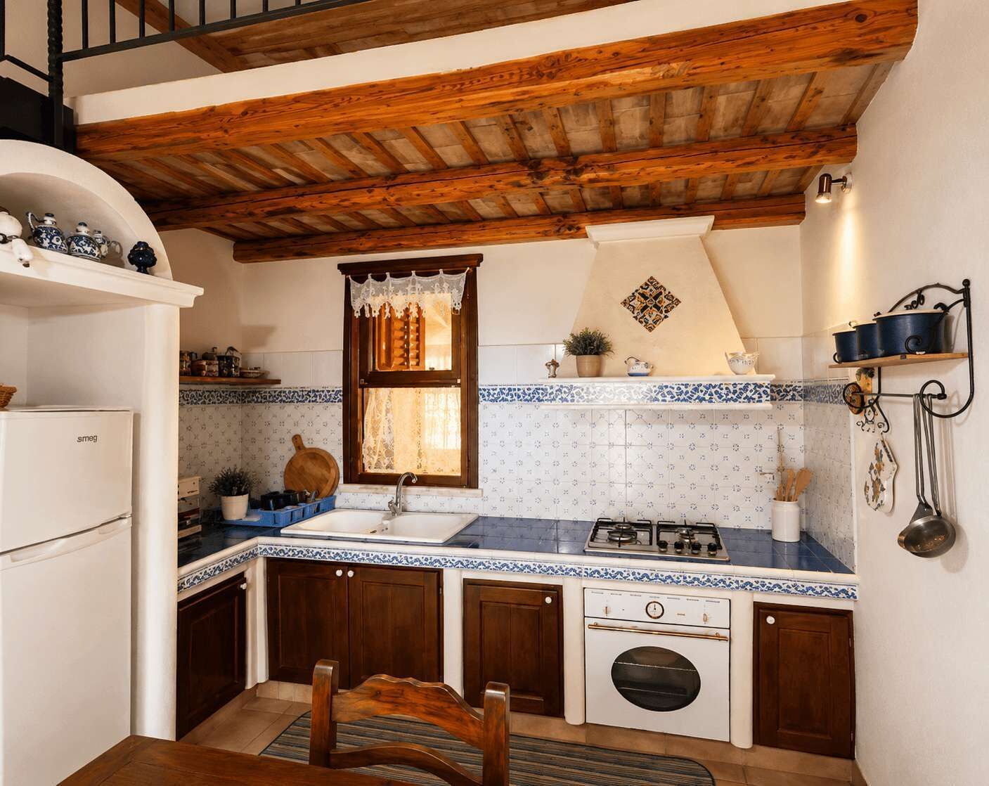Une cuisine compacte avec un plafond en bois, une cuisinière, un évier et un petit four.