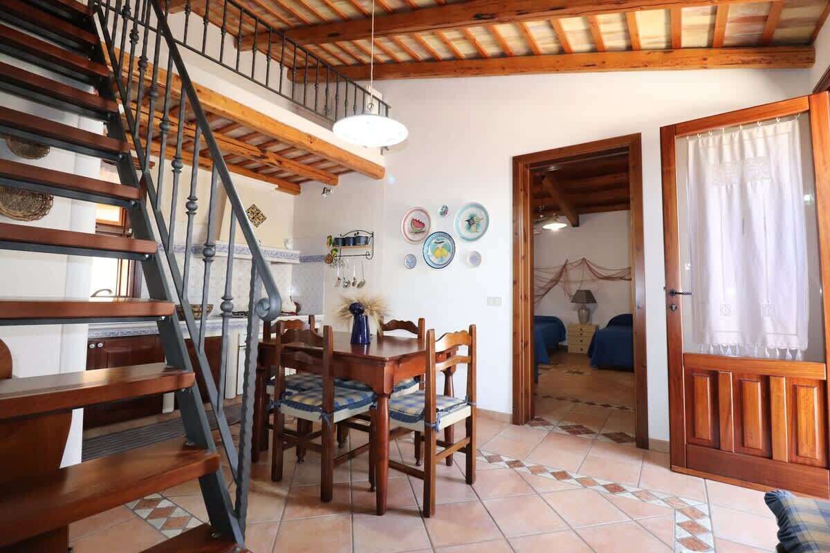 Un espace repas avec des meubles en bois, un escalier et une vue sur une autre pièce.