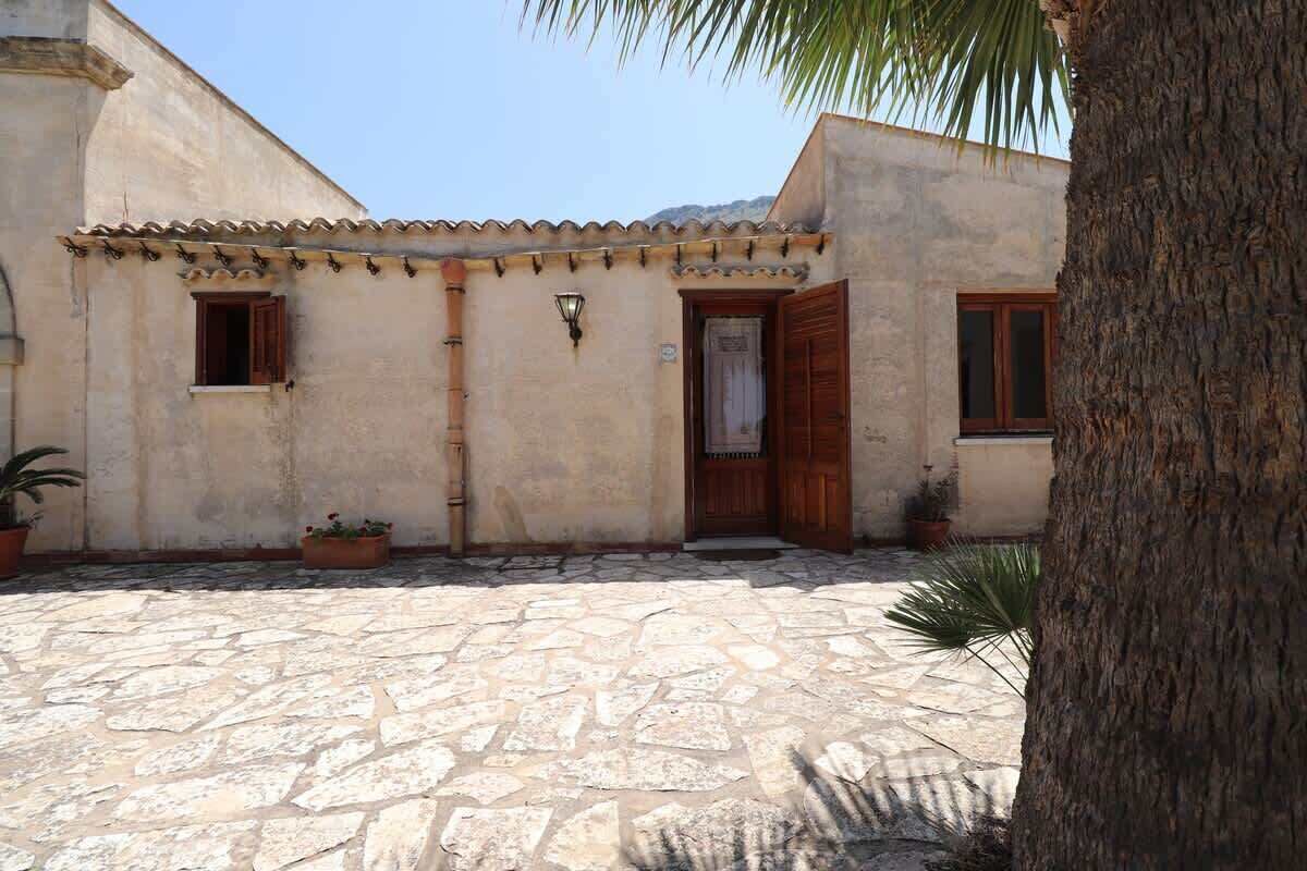 A building with a stone courtyard, wooden doors, and potted plants.