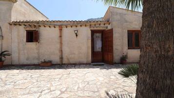 A building with a stone courtyard, wooden doors, and potted plants.
