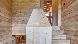 A wooden staircase with a skull mounted on the wall above. - Chalet Lessner - Pure Design & Tranquility (Leutasch)