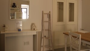 Ein Zimmer mit einem Bett, einem Schreibtisch mit Spiegel, einem Stuhl, einer Holzleiter und einer Tür mit satinierten Glasscheiben.