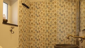 Een badkamer met een douche, een wastafel met een grote wasbak, een toilet en een plank met toiletartikelen.