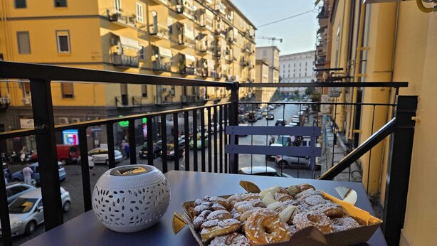 A balcony with a table holding a basket of pastries and a decorative item. - Modern vacation home for couples and families - central area (Napoli)