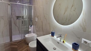 A modern bathroom with a large mirror, a white sink, and a shower area. - Modern vacation home for couples and families - central area (Napoli)