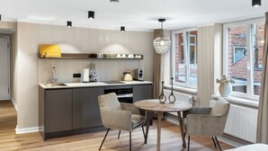 Ett modernt kök med en köksö i mitten, en matplats med två stolar och ett stort fönster med utsikt över en byggnad med tegelstensfasad.
