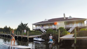 A waterfront property with a dock, paddleboards, and a small boat. - The Kite Club - Canal Front, All One level - 4 Bedroom House, Pool, Large Docks (Avon)