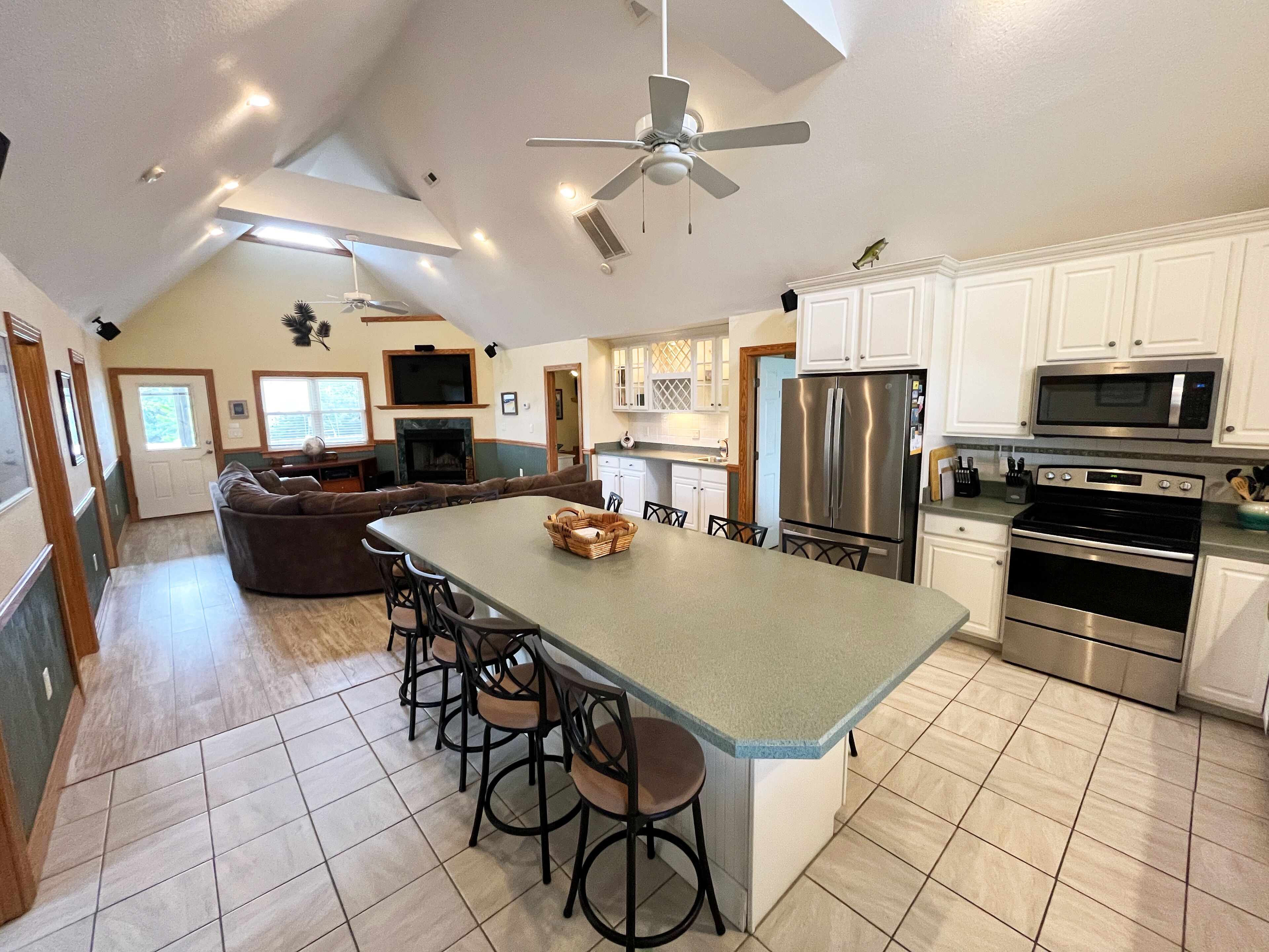 A spacious kitchen with a large island, stainless steel appliances, and a ceiling fan.
