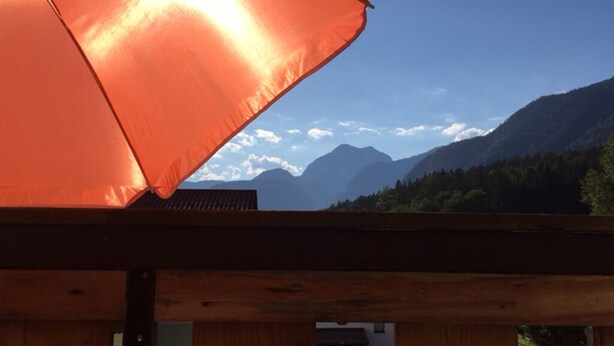 A wooden deck with a view of mountains and a clear sky.