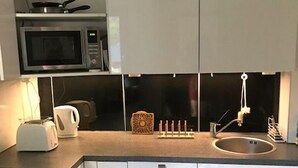 A modern kitchen with white cabinets, a microwave, a toaster, and a sink.