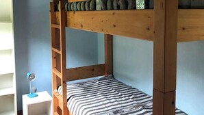 A bunk bed with a wooden frame, a ladder, and a striped mattress.