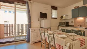 Une cuisine compacte avec un coin repas, un téléviseur et un balcon offrant une vue agréable.