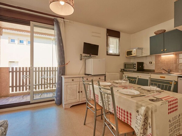 A compact kitchen with a dining area, a TV, and a balcony with a view. - Bright T2 in Barbotan with Wifi and pets allowed (Barbotan-les-Thermes)