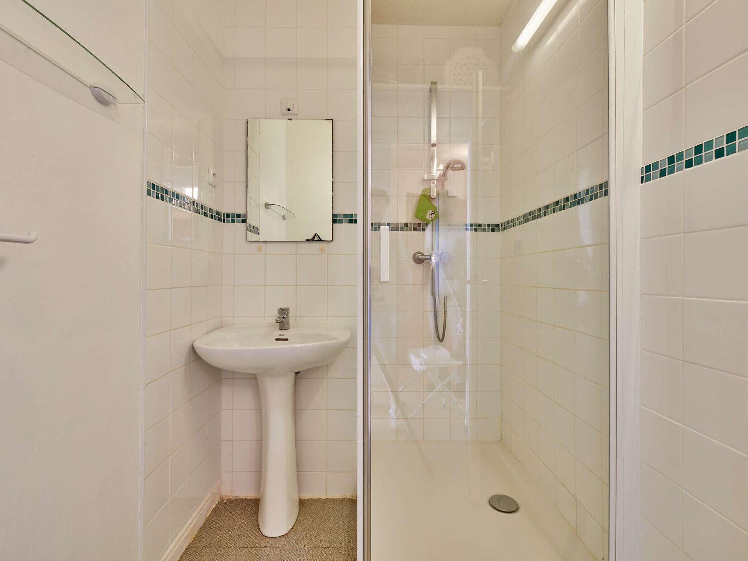 A bathroom with a pedestal sink, a mirror, and a shower enclosure.