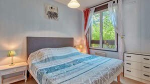 A bedroom with a bed, bedside tables, a dresser, a window with curtains, and a wall-mounted picture.