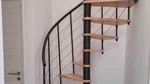 Una escalera de caracol con escalones de madera y barandillas de metal negro.