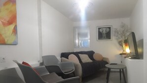 Una sala de estar moderna con un sofá, dos sillones, una mesita redonda, un espejo y un cuadro en la pared.
