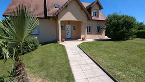 A two-story house with a tiled roof, a front porch, and a paved driveway leading to the entrance.