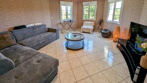 A living room with a grey sofa, a round coffee table, a TV, and a piano.