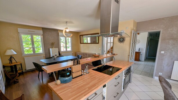 A modern kitchen with a central island, a built-in stove, and a large window providing natural light.