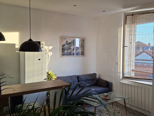 Een moderne woonkamer met een bank, een glazen salontafel, een hanglamp en een ingelijste foto aan de muur.