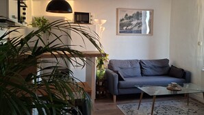 A living room with a sofa, a glass coffee table, a TV, and a framed picture on the wall.