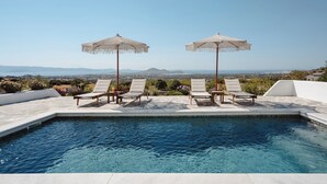 A pool with two umbrellas, four lounge chairs, and a view of distant mountains. - Villa THÉA I, Villa THÉA Naxos (Naxos)