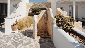 A white building with a stone pathway, a small archway, and outdoor seating. - Villa THÉA I, Villa THÉA Naxos (Naxos)