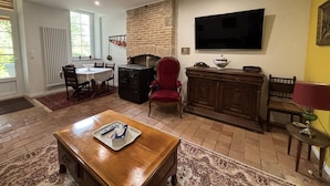 Un salon doté d’une cheminée, d’un téléviseur fixé au mur et d’un coin repas avec une table et des chaises.