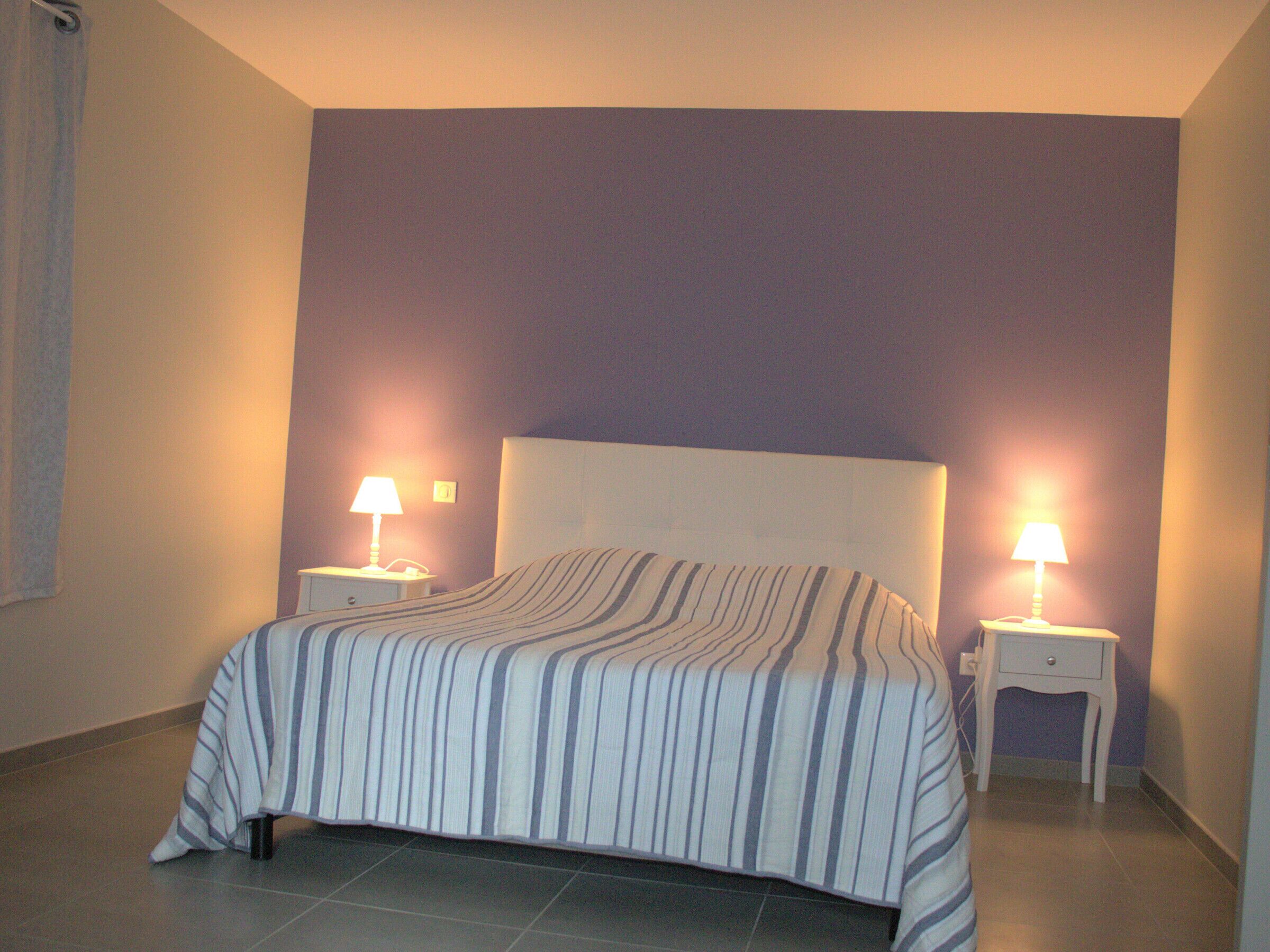 Une chambre à coucher avec un lit, deux tables de chevet et deux lampes.