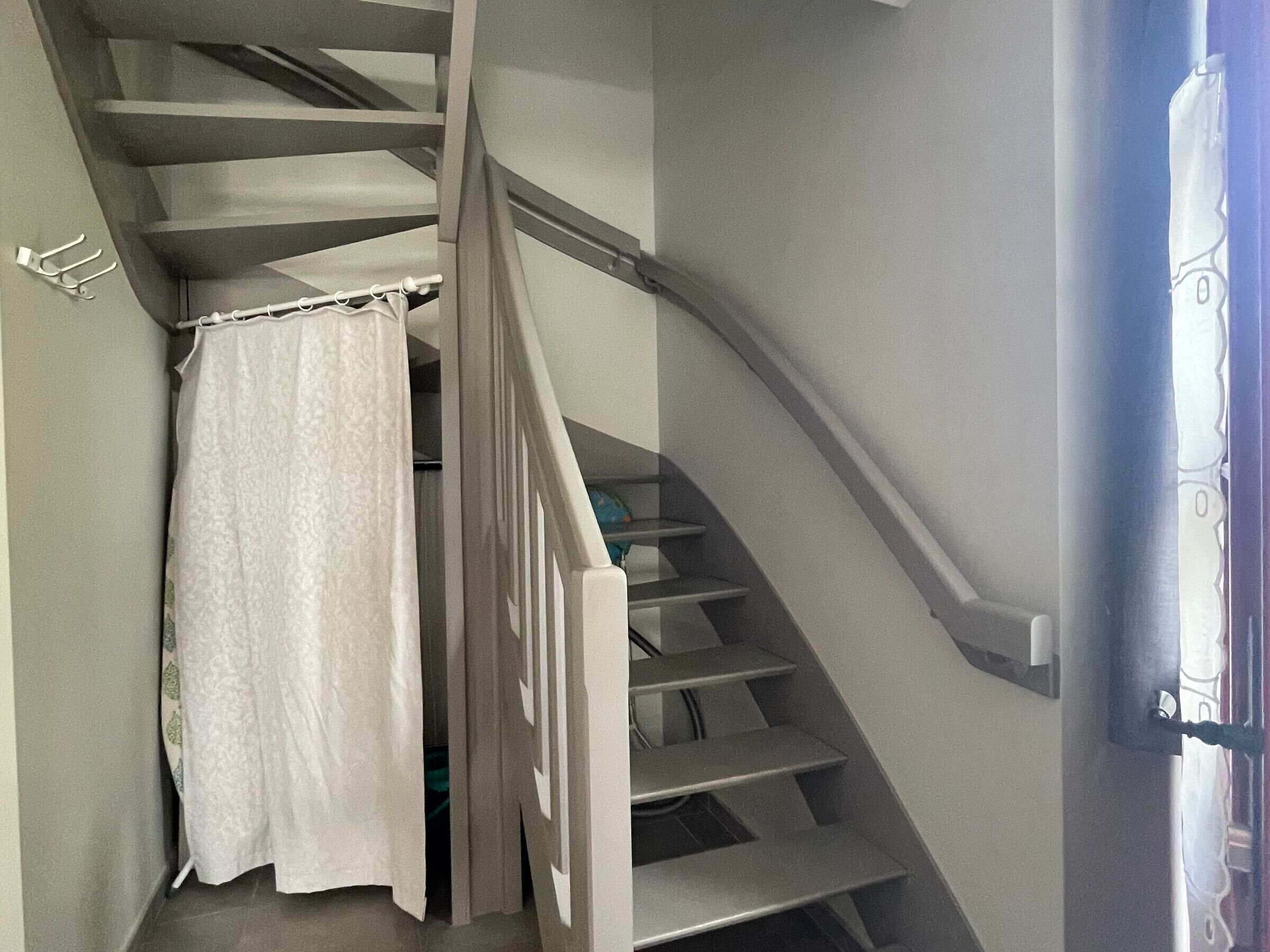 Un escalier avec une rampe blanche et un rideau blanc en bas.