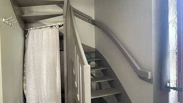 Un escalier avec une rampe blanche et un rideau blanc en bas.