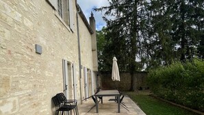 A patio with a table and chairs, a stone wall, and a tree.