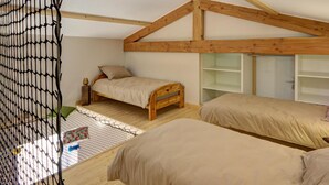 A bedroom with a sloped ceiling, wooden beams, two beds, a small table, and a lamp. - Family cottage with fiber, in the peaceful Monts du Lyonnais (Panissières)