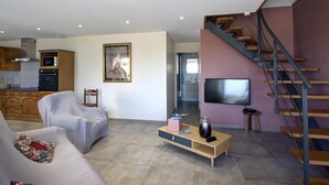 A modern living room with a sofa, a coffee table, a TV, and a staircase. - Family cottage with fiber, in the peaceful Monts du Lyonnais (Panissières)