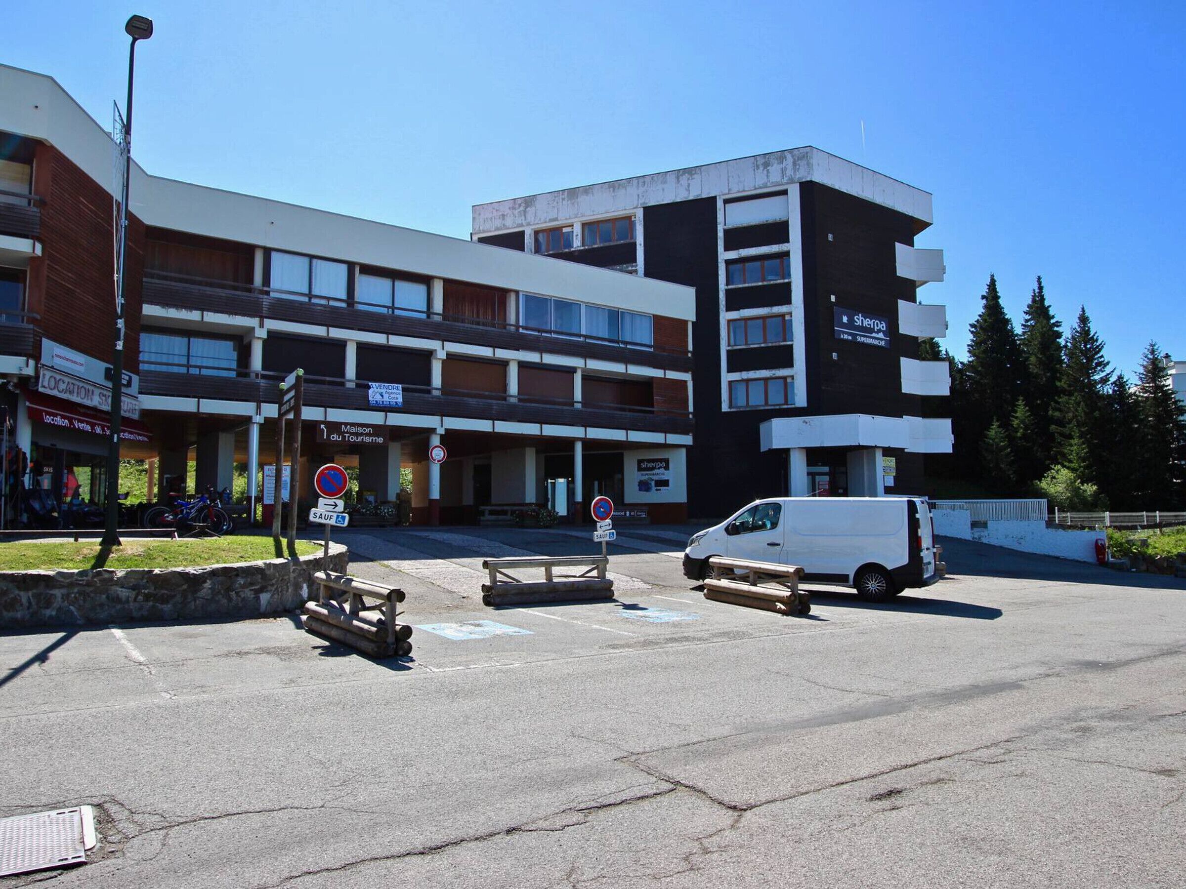 A multi-story building with a sign for 'Maison du Tourisme' and a Sherpa supermarket.