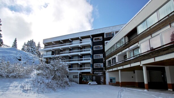 Un hotel a più piani con facciata innevata e un'area parcheggio.