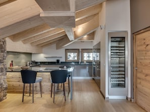 A modern kitchen with a central island, bar stools, and a built-in oven.