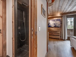 A wooden interior with a shower, a painting, and a view of a building outside. - Luxury Penthouse in Val-d'Isère with Fireplace and Parking (Val-d'Isère)