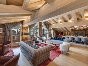 A spacious living area with a sofa, chairs, a dining table, and a dog. - Luxury Penthouse in Val-d'Isère with Fireplace and Parking (Val-d'Isère)