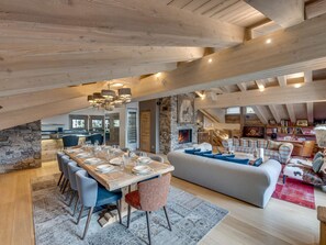 A spacious loft with exposed wooden beams, a stone fireplace, and a cozy seating area. - Luxury Penthouse in Val-d'Isère with Fireplace and Parking (Val-d'Isère)