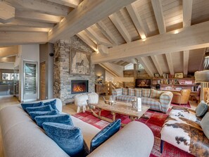 Una sala de estar acogedora con chimenea de piedra, vigas de madera y un espacio de descanso cómodo.